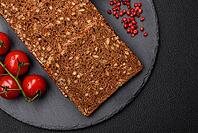 Food, Delicious fresh crispy brown bread with seeds and grains cut into slices on a dark concrete background [IBR124842108]