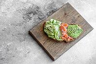 Food, Delicious brown bread toast with salmon, avocado, cucumber and sesame seeds on a textured concrete background [IBR124876416]
