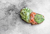 Food, Delicious brown bread toast with salmon, avocado, cucumber and sesame seeds on a textured concrete background [IBR124876420]