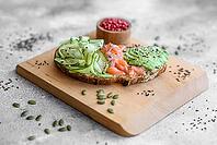 Food, Delicious brown bread toast with salmon, avocado, cucumber and sesame seeds on a textured concrete background [IBR124876422]