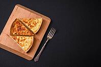 Food, Beautiful delicious quiche pie with four types of cheese with spices and herbs on a dark concrete background [IBR124876441]