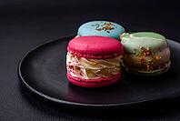 Food, Beautiful tasty macaron with filling and fruit flavor on a black plate on a dark concrete background [IBR124876443]