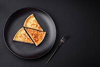Food, Beautiful delicious quiche pie with four types of cheese with spices and herbs on a dark concrete background [IBR124876444]