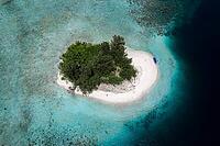 Aerial view from top to bottom of a small tropical island with white sandy beach and a boat and a presented reef, Raja Ampat, West Papua, Indonesia [IBR124899548]