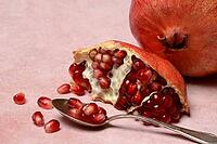 Opened pomegranate and pomegranate seeds in a spoon, Punica granatum [IBR124899848]