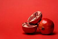 Pomegranate with red background, Punica granatum, cut in half [IBR124899849]
