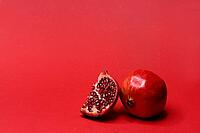 Pomegranate with red background, Punica granatum, cut in half [IBR124899855]