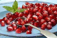 Pomegranate seeds and spoons on plate, Punica granatum [IBR124899856]