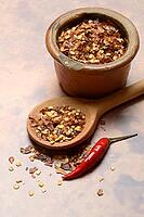 Chilli, chilli flakes in cooking spoon and pot, Capsicum annuum [IBR124899859]