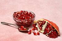 Opened pomegranate and pomegranate seeds in bowl and spoon, Punica granatum [IBR124899861]