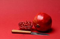 Pomegranate with red background, Punica granatum, cut in half [IBR124899862]