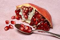 Opened pomegranate and pomegranate seeds in a spoon, Punica granatum [IBR124899866]
