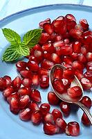 Pomegranate seeds and spoons on plate, Punica granatum [IBR124899868]