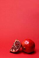Pomegranate with red background, Punica granatum, cut in half [IBR124899871]