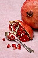Opened pomegranate and pomegranate seeds in a spoon, Punica granatum [IBR124899872]