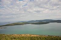 A tranquil panorama of Ayvalık's emerald islands and calm waters unfolds beneath soft, drifting clouds [IBR124899886]