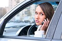 Sensual young woman is looking at camera from a car and talking phone [IBR124906344]