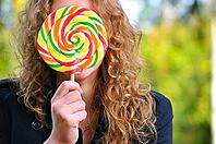 Woman is hiding behind a huge lollipop [IBR124906354]