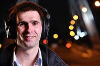 Smiling man is listening music at city night street [IBR124906390]