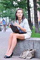 Beautiful woman is sitting in an alley with laptop and looking sideways [IBR124906399]