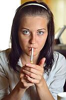 Young woman is lighting a cigarette in a cafe [IBR124906401]