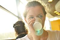 Woman is drinking from paper cup [IBR124906409]
