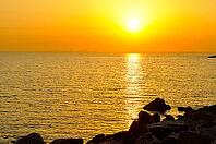 Sunrise in sea with city on skyline [IBR124906412]