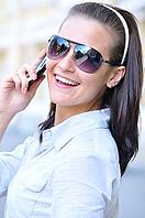 Happy woman is looking back and talking phone [IBR124906413]
