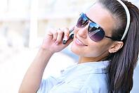 Happy woman is looking back and talking phone [IBR124906414]