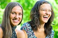 Two female friends is laughing in sunny park [IBR124906421]