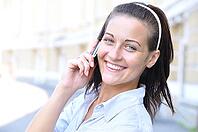 Beautiful smiling woman is talking phone at sunny street [IBR124906422]
