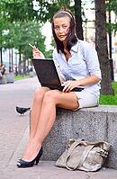 Young woman is closing laptop after work at city park [IBR124906423]