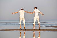 Two friends is jumping at morning beach [IBR124906424]