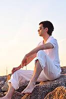 Man is sitting on stones at sunrise [IBR124906425]
