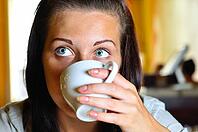 Young woman is drinking coffee in cafe and looking sideways [IBR124906426]