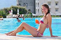 Sexy woman is sitting at poolside with cocktail [IBR124906429]