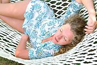 Sexy woman is lying in hammock at summer in park [IBR124906430]