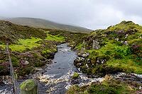 View of the Scottish Highlands, green meadows, cloudy skies and a river in summer 2018 [IBR124915230]