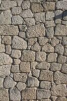 Close view of aged stone wall showing rough texture, natural pattern, and rustic architectural detail [IBR124920162]