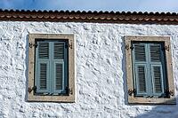 A vibrant rustic windows Mediterranean charm through vivid shutters and textured stone facades [IBR124920194]