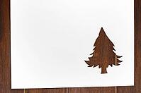 Cut paper in fir-tree shape for christmas card or new year background on wooden table [IBR124944041]