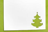 Cut paper in fir-tree shape for christmas card or new year background on green table [IBR124944059]