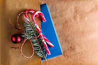 Christmas or new year decoration for gift box of two candy cones with fir-tree branch and toy glass ball on craft paper background [IBR124944072]