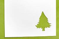 Cut paper in christmas tree shape for christmas card or new year background on green table [IBR124944075]