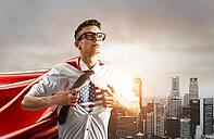 USA Superhero. Young businessman showing American flag under his shirt against sunset city [IBR124944105]