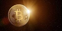 Bitcoin in starry space with rising sun behind [IBR124944106]