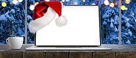 Laptop on table with Santa Claus hat at home with panoramic view through window of snowy trees in winter forest, screen is cut with provided clipping path [IBR124944127]