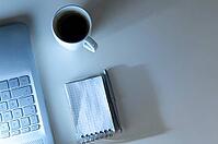 Modern laptop on evening work place, coffee cup and notebook with pen, view from above [IBR124944133]