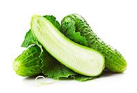 Heap of fresh green cucumbers with leaf and yellow flowers. Placed on white background. Close-up [IBR124991164]