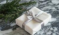 Neatly wrapped white gift with a silver ribbon, positioned on a marble table next to a sprig of fir. AI generated [IBR125000271]